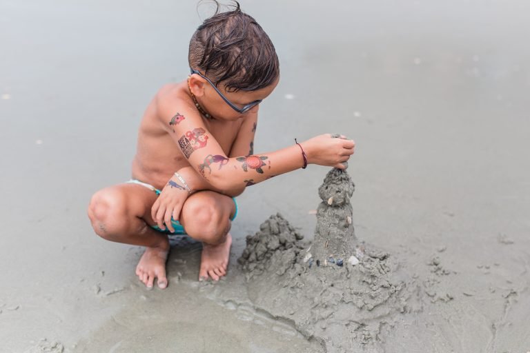 A child building intricate sand castles on the beach, capturing the essence of ephemeral play and beach creativity.